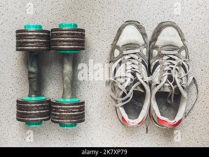 Chaussures de sport vintage et haltères sur le sol, vue du dessus. Arrière-plan sportif Banque D'Images