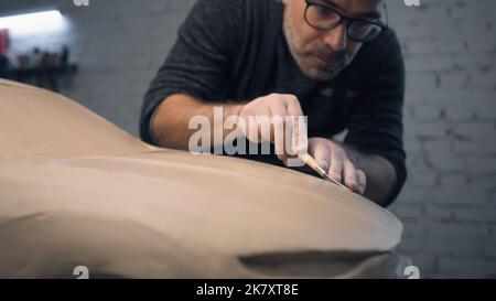 Le concepteur de voiture travaille en étroite collaboration sur la sculpture d'un prototype de voiture à l'aide d'un outil à pointe de fil pour sculpter la conception de voiture. Apporte des modifications à la conception et la perfectionne. Modèle prototype de la voiture. Banque D'Images