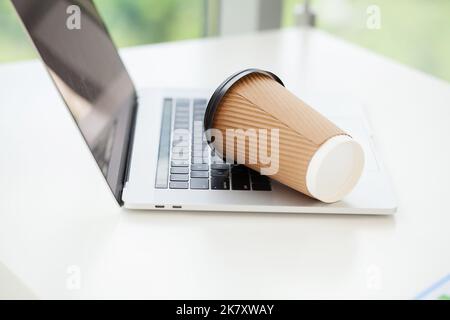 Versez du café sur le clavier de l'ordinateur portable à partir du verre de papier Banque D'Images