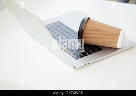 Versez du café sur le clavier de l'ordinateur portable à partir du verre de papier Banque D'Images