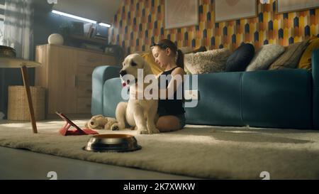 Jeune fille jouant avec le chien avec le jouet et le ballon, assis sur un tapis doux, nourrissant le chiot, parlant et s'amusant avec l'animal de compagnie, passant du temps libre à la maison. Golden Retriever. Banque D'Images