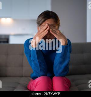 La femme pensive assise sur le canapé a la dépression et la mélancolie après avoir brisé avec le petit ami Banque D'Images