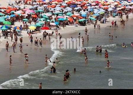 Plage de Leblon, Rio de Janeiro, Brésil. Les gens se bronzent près de la rive avec des parasols colorés. La foule aime nager en mer en été. Voyage tropical Banque D'Images