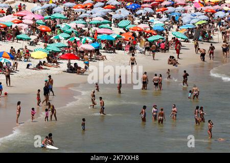 Plage de Leblon, Rio de Janeiro, Brésil. Les gens se bronzent près de la rive avec des parasols colorés. La foule aime nager en mer en été. Voyage tropical Banque D'Images