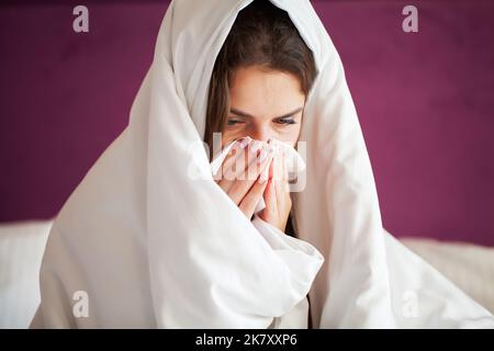 Une jeune femme infectée par un rhume souffle son nez avec un mouchoir Banque D'Images