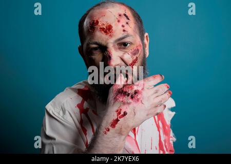 Fou halloween zombie piquant main sanglante avec des cicatrices et des blessures, étant agressif et dangereux. Monstre maléfique sans mort avec un regard apocalyptique sur le démon et un visage effrayant, un cadavre cruel blessé. Banque D'Images