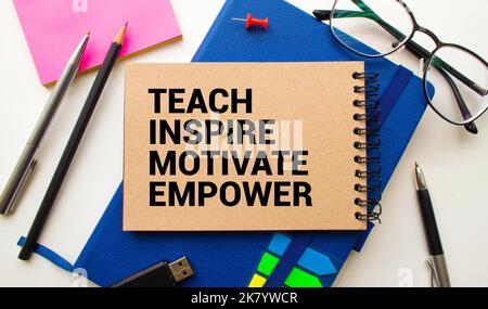 Cahier ouvert avec texte enseigner inspirer motiver Empower sur fond de bois. Banque D'Images