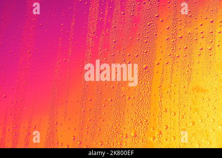 Gouttes d'eau dans des lumières colorées . Arrière-plan multicolore humide Banque D'Images