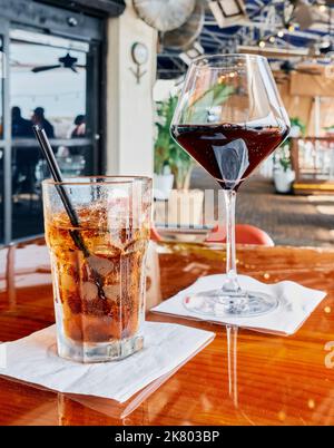 Boisson mélangée peut-être un Bourbon et Coca-Cola ou un Rum et Coca-Cola avec un verre de vin rouge sur une table de restaurant à destin Floride, Etats-Unis. Banque D'Images