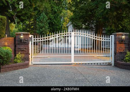 Porte d'entrée en fer d'une maison de luxe. Porte blanche en fer forgé et pilier en brique. Personne, photo de rue, mise au point sélective Banque D'Images