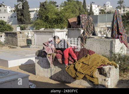 Un enfant palestinien joue devant sa maison dans le cimetière Sheikh Shaban de la ville de Gaza. Taux de chômage élevés et manque de possibilités d'emploi à Gaza, et nombre croissant de familles confrontées à la pauvreté après avoir perdu un emploi au cours des dix dernières années du blocus de Gaza. Une bataille pour l'espace entre les vivants et les morts fait rage alors que les sans-abri s'installent dans les cimetières de la région tandis que les autorités sont aux prises avec la demande croissante de nouveaux logements. Kahil a dit: Si les morts parlaient, ils nous diraient de sortir d'ici. Qui vivait dans le cimetière du centre de Gaza avec son mari et une famille de six non Banque D'Images