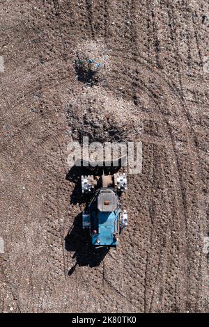 Vue aérienne directement au-dessus d'une machine à bulldozer déplaçant les déchets et les ordures ménagères sur un grand tas de décharge avec un espace de copie Banque D'Images