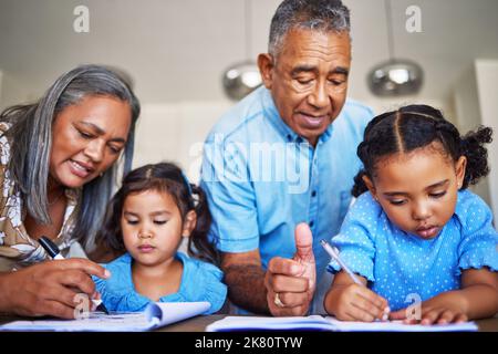 Devoirs, écriture et grands-parents aider les enfants avec l'éducation ensemble à une table dans leur maison. Les filles apprennent dans un ordinateur portable avec un aîné Banque D'Images