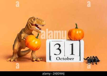 Jouet dinosaure Tyrannosaurus, potiron, date du calendrier 31 octobre, araignée isolée sur fond orange carte de voeux de vacances joyeux jour d'Halloween créatif Banque D'Images