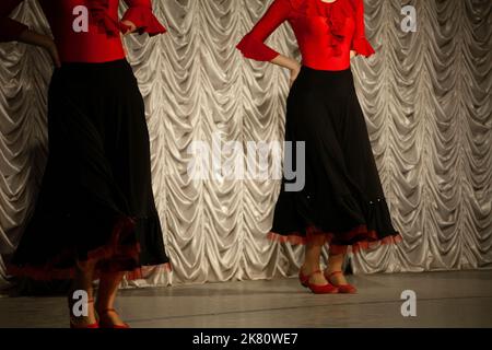 Danse espagnole. Filles dansant dans des robes noires. Leçon de danse. Traditions espagnoles. Vêtements rouges. Danseurs sur scène. Banque D'Images