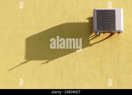 Climatiseur sur un mur jaune avec ombre Banque D'Images