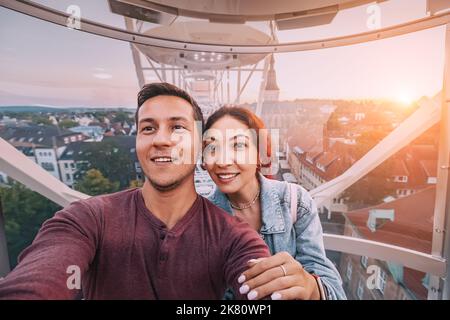 Un couple amoureux prend une photo de selfie tout en datant dans un stand de roue de Ferris dans un parc d'attractions mobile dans le centre de la vieille ville d'Osnabruck en UE Banque D'Images