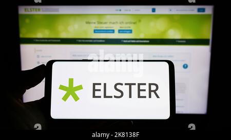 Personne tenant un téléphone portable avec le logo du logiciel fiscal allemand Elster à l'écran en face de la page web. Mise au point sur l'affichage du téléphone. Banque D'Images