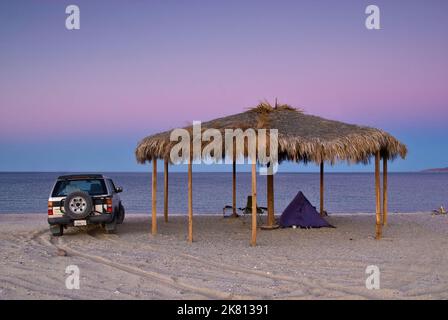 Campeur à Palapa sur la plage après le coucher du soleil à Bahia San Luis Gonzaga à Campo Rancho Grande, Baja Californie, Mexique Banque D'Images