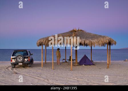 Campeur à Palapa sur la plage après le coucher du soleil à Bahia San Luis Gonzaga à Campo Rancho Grande, Baja Californie, Mexique Banque D'Images