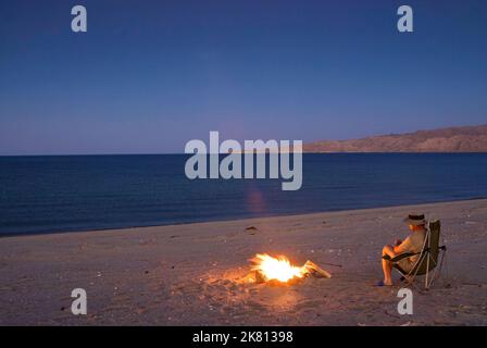 Campeur au feu sur la plage après le lever du soleil à Bahia San Luis Gonzaga à Campo Rancho Grande, Baja Californie, Mexique Banque D'Images