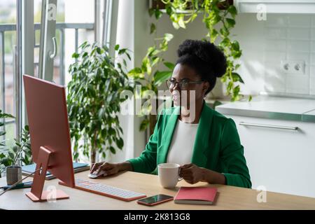 La jeune femme afro-américaine secrétaire travaille au bureau avec un ordinateur et du café Banque D'Images