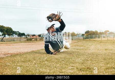 Baseball, sports et capture avec un homme athlète attrapant une balle pendant un match ou un match sur un terrain de sport. Fitness, exercice et entraînement avec un Banque D'Images