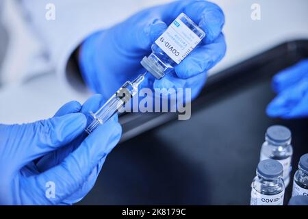 Chaque dose permet de sauver des vies. Un scientifique méconnaissable utilisant une seringue pour extraire le vaccin Covid 19 d'un flacon en laboratoire. Banque D'Images