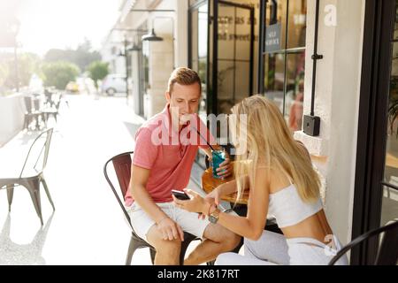 Jeune couple assis dans un café et utilisant un smartphone. Les étudiants pendant la pause dans le café place.appréciant une grande première date. Banque D'Images