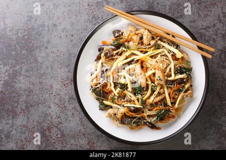 Aliments coréens sautés avec des nouilles, de la viande, des champignons et des légumes appelés Japchae sur l'assiette de la table. Vue horizontale du dessus Banque D'Images