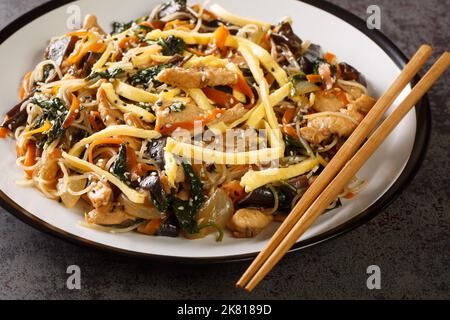 Japchae Korean Stir-frit nouilles de verre et légumes closeup sur l'assiette sur la table. Horizontale Banque D'Images