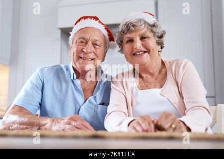 Vous m'avez affronté avec des berceuses. Portrait d'un couple âgé portant des chapeaux de fête à la table ensemble à la maison. Banque D'Images