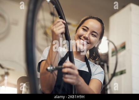 De retour du bleu, rien de nouveau. Portrait d'une jeune femme tenant une roue de vélo au travail. Banque D'Images