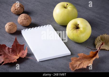Composition automnale de feuilles sèches, pommes, noix bloc-notes blanc. Banque D'Images