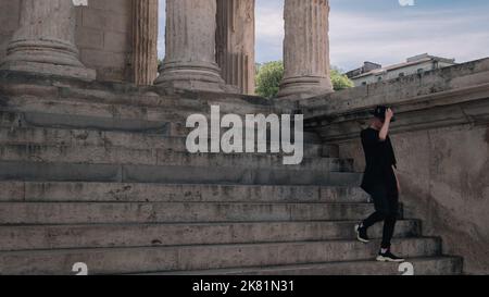 Homme marchant sur les marches de la Maison Carree à Nîmes, France. Printemps dans le sud de la France. Banque D'Images