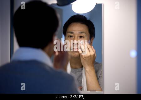 Homme japonais appliquant la crème pour le visage Banque D'Images