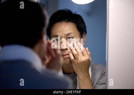 Homme japonais appliquant la crème pour le visage Banque D'Images