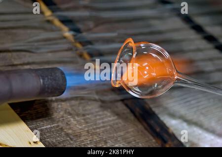 Gros plan d'un morceau de verre en fusion et de flamme qui sera un magnifique ornement de noël Banque D'Images