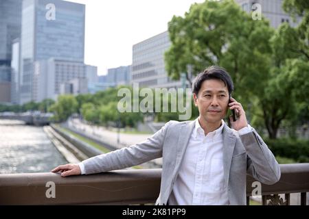 Homme d'affaires japonais sur le téléphone Banque D'Images