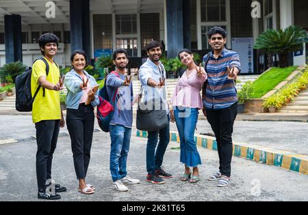 plein cliché des étudiants confiants avec sac à dos et des livres montrant les pouces en regardant l'appareil photo sur le campus universitaire - concept d'approbation, éducation et Banque D'Images