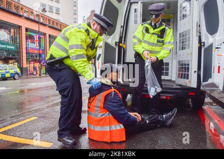 Londres, Royaume-Uni. 20th octobre 2022. La police arrête un manifestant. Les activistes Just Stop Oil ont collé leurs mains et se sont attachés à des tuyaux métalliques sur Brompton Road à l'extérieur de Harrods, et ont pulvérisé de la peinture orange sur les fenêtres du célèbre grand magasin de Knightsbridge, alors qu'ils poursuivent leurs protestations exigeant que le gouvernement cesse d'émettre de nouvelles licences de combustibles fossiles. Credit: Vuk Valcic/Alamy Live News Banque D'Images