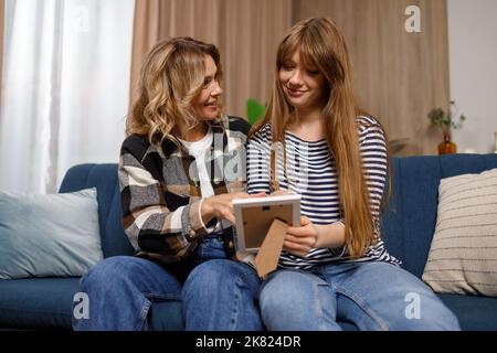Femme adulte et fille adulte souriant regardant la photo dans le cadre à la maison Banque D'Images