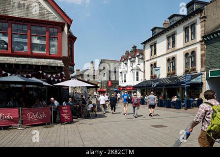 Personnes touristes visiteurs magasins magasins dans le centre-ville en été main Street Keswick Cumbria Angleterre Royaume-Uni GB Grande-Bretagne Banque D'Images