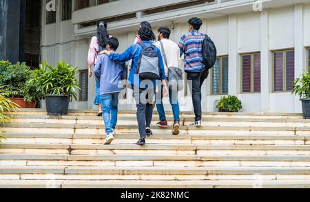 Vue arrière des élèves avec sac à dos aller à la salle de classe au campus de l'université - concept de retour à l'école, amitié et éducation. Banque D'Images
