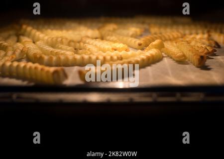 Gros plan de frites jaunes fraîches hollandaises cuites au four chaud. Préparation du dîner. Jetons. Banque D'Images