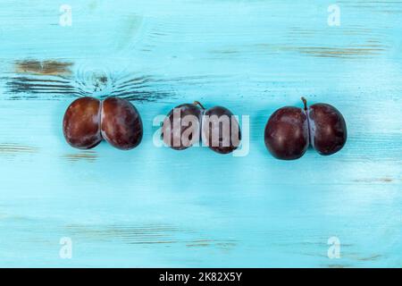 Un concept de cuisine tendance et injurieux. Prunes sur fond bleu. Fruit de forme étrange. Le problème des déchets alimentaires. Banque D'Images