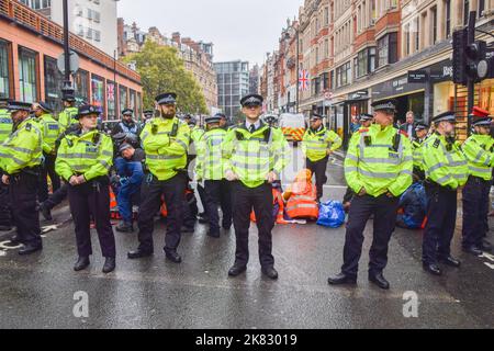 Londres, Royaume-Uni. 20th octobre 2022. Les activistes Just Stop Oil ont collé leurs mains et se sont attachés à des tuyaux métalliques sur Brompton Road à l'extérieur de Harrods, et ont pulvérisé de la peinture orange sur les fenêtres du célèbre grand magasin de Knightsbridge, alors qu'ils poursuivent leurs protestations exigeant que le gouvernement cesse d'émettre de nouvelles licences de combustibles fossiles. Banque D'Images