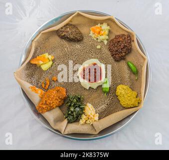 Repas typique en Ethiopie - Beyainatu. Un peu de tout. Mélanger les légumes et les ragoûts sur le pain plat injera. Banque D'Images