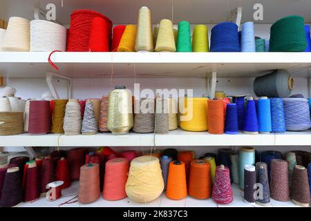 Cônes et bobines de fil à coudre coloré organisés en couleur rouge, orange, jaune, bleu Banque D'Images