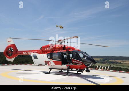 PRODUCTION - 22 juin 2022, Thuringe, Bad Berka : l'hélicoptère de secours « Christoph Thüringen » se dresse sur le toit de Zentralklinik, tandis qu'un hélicoptère de secours ADAC survole derrière lui. L'hélicoptère est l'un des quatre stationnés en Thuringe et le seul qui peut également voler des missions de nuit. Photo: Bodo Schackow/dpa Banque D'Images